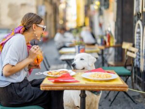 Woman sitting at an outdoor table at a restaurant with her dog